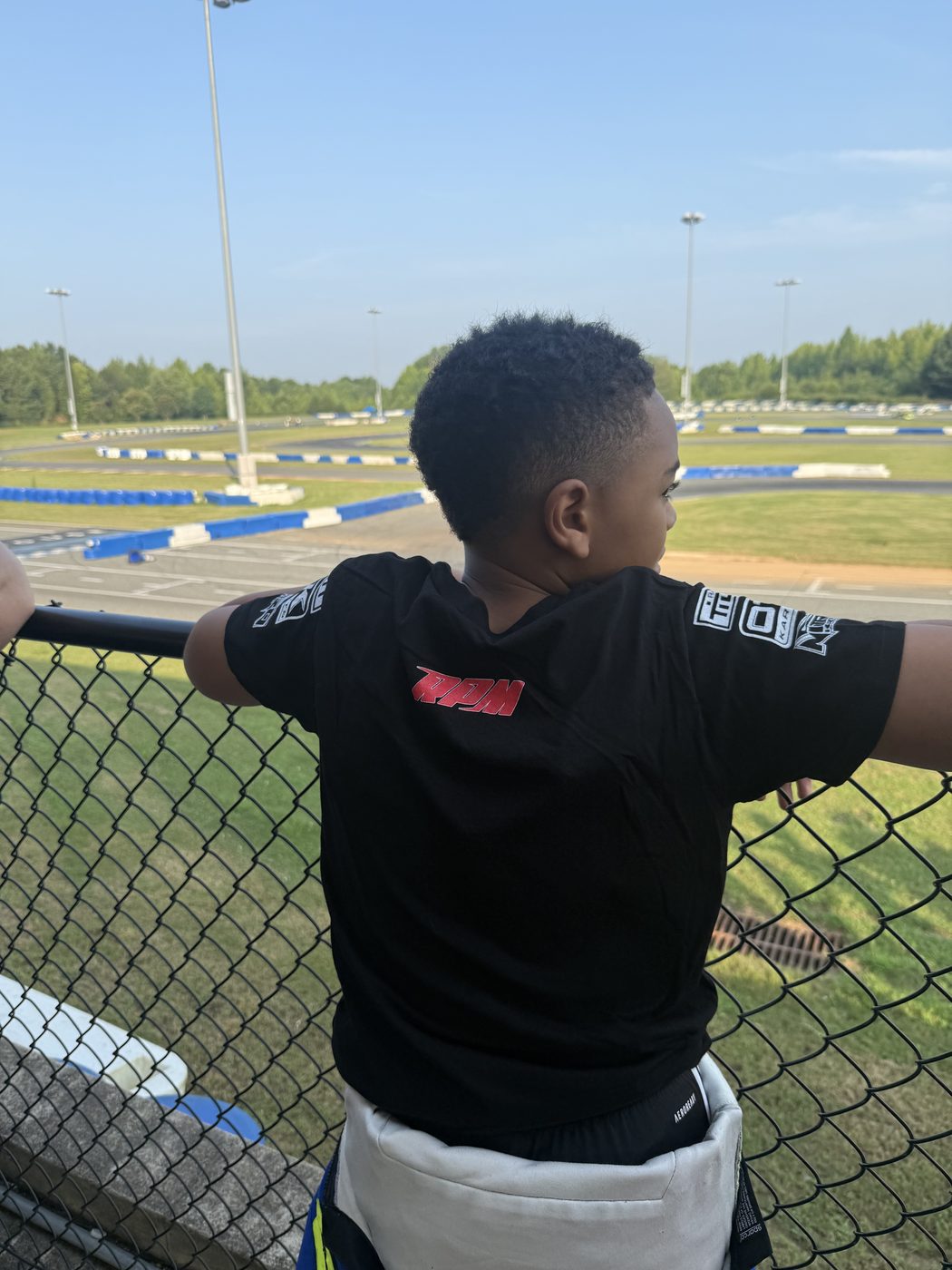Kaz at the fence watching the track, RPM shirt